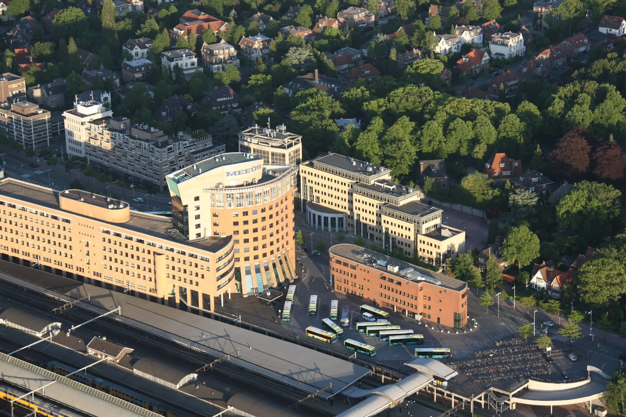 Luchtfoto van het kantoorgebouw aan de Barchman Wuytierslaan in Amersfoort met bussen, fietsenstalling en het naastgelegen station.